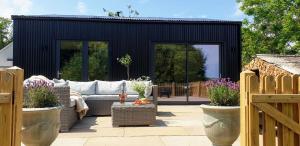a patio with a couch in a black shed at Finest Retreats - Blackbarn Wood in Balsham