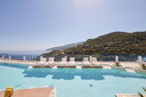 a large swimming pool with lounge chairs and the ocean at Sea View Kerame in Évdhilos