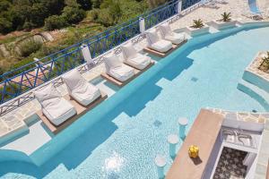 a swimming pool with chaise lounges and chairs on a resort at Sea View Kerame in Évdhilos