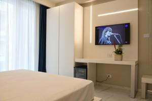 Cette chambre comprend un lit et une télévision murale. dans l'établissement DEMSI Palace Hotel & Restaurant, à Foggia