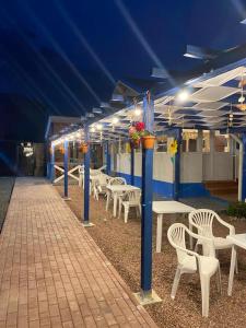 a row of tables and chairs on a patio at night at Pensiunea Blue House in Vadu