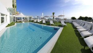 a large swimming pool with white lounge chairs and tables at Hotel Mediterraneo in Riccione