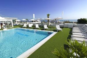 a swimming pool with lounge chairs and the ocean at Hotel Mediterraneo in Riccione