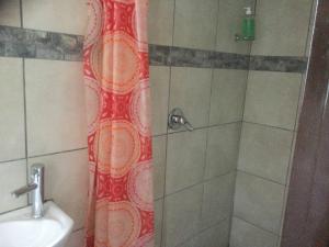 y baño con ducha con cortina de ducha roja. en Ruros Guest House en Kempton Park