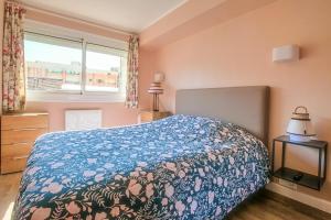 una camera da letto con un letto con una coperta blu e una finestra di La Douce Vie a Le Touquet-Paris-Plage