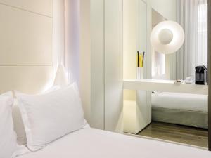 a hotel room with white walls and a white bed at H10 Urquinaona Plaza in Barcelona