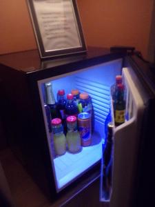 una nevera llena de botellas y latas de bebidas en chambre avec spa privatif en Loon-Plage