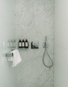 a bathroom with a shower with white marble walls at Hôtel Hemen in Saint-Palais-sur-Mer