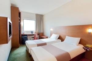 um quarto de hotel com duas camas e uma televisão em ibis Amman em Amã