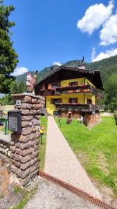 a large yellow house with a stone wall next to it at Villa L'Aida in Canazei