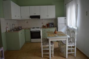 uma cozinha com armários brancos, uma mesa e um frigorífico em La Casa Azul - Blue House - Το Μπλε Σπίτι em Sitia