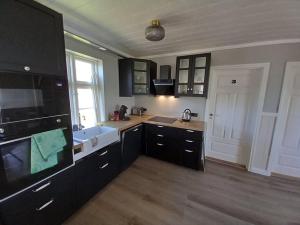 a kitchen with black cabinets and a sink at Pálshús in Patreksfjörður