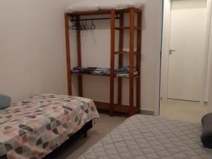 a bedroom with a bed and a shelf with clothes at Apartamento 103 novo 100 mts da Praia Espanha Residence in Florianópolis