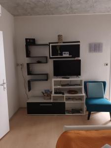 ein Wohnzimmer mit einem TV und einem blauen Stuhl in der Unterkunft Studio Jadranka in Bale