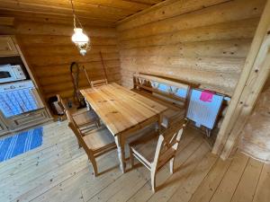 a dining room with a wooden table and chairs in a cabin at TRINITY Log Cabin Wellness resort in Štrba