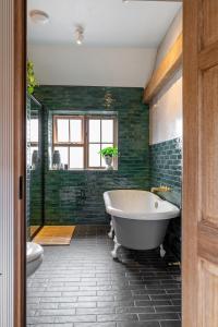 y baño con bañera y azulejos verdes. en Crabtree Farm - South Stable, en Ashford
