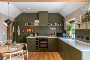 a kitchen with green cabinets and a wooden table at Crabtree Farm - South Stable in Ashford