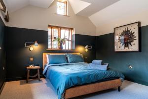Schlafzimmer mit einem Bett mit blauer Bettwäsche und blauen Wänden in der Unterkunft Crabtree Farm - South Stable in Ashford