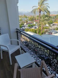 a balcony with chairs and a table and a palm tree at Narac Dom in Fethiye +4 photos