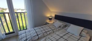 a bedroom with a bed and a large window at Domki Puszek in Łeba