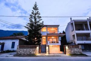 a house with a pine tree in front of it at Aigli Luxurious Villa in Káto Pitsá