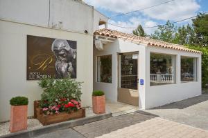 a store with a sign on the side of a building at Logis Hôtel Le Rodin in Arles
