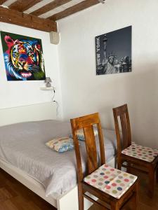 a room with a bed and two chairs and a picture at Appartement SEPHORA in La Neuveville