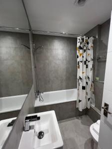 a bathroom with a sink and a bath tub at Pearl & Pebbles Eastbourne in Eastbourne