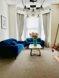 Pearl & Pebbles Eastbourne في إيستبورن: غرفة معيشة مع أرائك زرقاء وطاولة مع الزهور