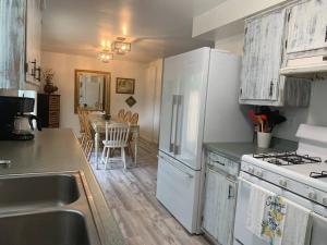 a kitchen with white appliances and a dining table at Cheerful 3 Bedroom on a Park 10 Miles from Eugene in Creswell