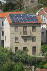 a stone house with solar panels on the roof at Casa Das Lages in Alvoco da Serra