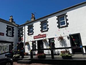 un edificio blanco con flores delante en The Village Inn en Carstairs