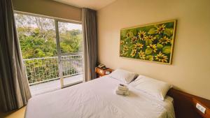a bedroom with a bed and a large window at Verde Vale Hotel in Videira