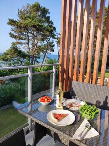 a glass table with a plate of food on a patio at Apartament BalticHoff w Let's Sea Baltic Park Gąski in Gąski