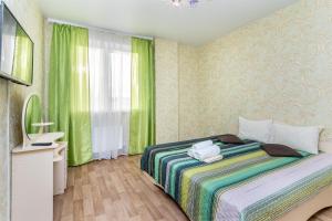 a bedroom with a bed with green curtains and a television at Апартаменты Central Park в центре Тюмени in Tyumen