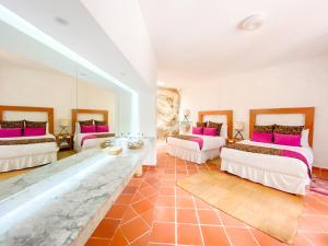 Habitación grande con 3 camas y almohadas rosas. en Molino de los Reyes By Rotamundos en Totolac