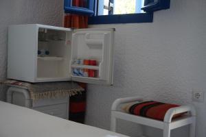 uma pequena cozinha com um frigorífico aberto e um banco em Michaela's em Drios