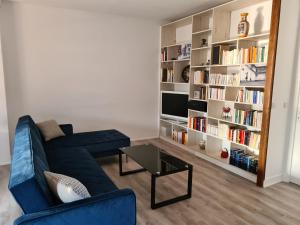 uma sala de estar com um sofá azul e uma estante de livros em 20 min de Disneyland - 4 chambres - 30 min Paris em Thorigny-sur-Marne