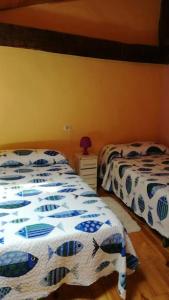 a bedroom with two beds and a table with a lamp at La casa azul del Pantano in La Costana