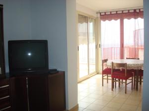 a living room with a tv and a table with chairs at Attico Con Vista Panoramica Sul Mare in Sciacca