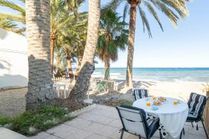 Bungalow Club Aguadulce 1 في روكويتاس دي مار: طاولة على الشاطئ مع أشجار النخيل والمحيط