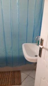 baño con lavabo y cortina de ducha azul en Vryses Crete-Village Vibes, en Vryses