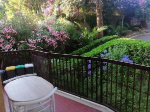 聖雷莫的住宿－Il Gioiello Nel Parco - Sanremo Apartments，一个带桌子的阳台和一个种满鲜花的花园
