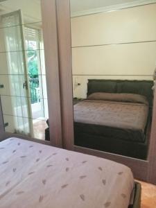 聖雷莫的住宿－Il Gioiello Nel Parco - Sanremo Apartments，卧室的镜子反射,卧室配有一张床和一张床的面积