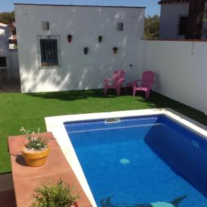 a swimming pool in a yard with chairs and a house at Delightful Villa close to the beach in L'Escala