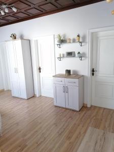 a kitchen with white cabinets and a wooden floor at Ferienhaus Savannah in Schützen am Gebirge