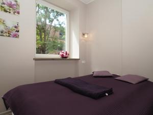 sypialnia z łóżkiem z fioletowymi prześcieradłami i oknem w obiekcie Grand-Tourist Apartments K2004 Simple Rest w Gdańsku
