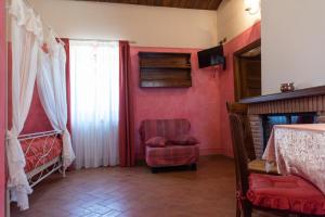 a bedroom with red walls and a chair and a window at Il Casale Di Ginetto in Cascia