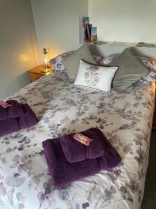 a bed with purple blankets and pillows on it at Rainors farm B&B in Gosforth
