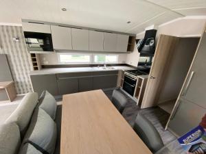 a small kitchen with a wooden table and chairs at 17 Wildflower Meadow in Chapel Saint Leonards